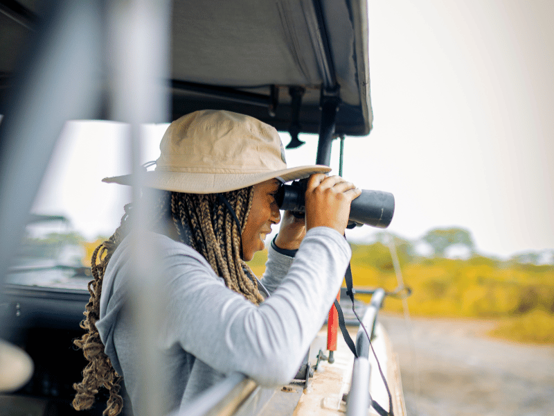 traveler looking out of a safari vehicle with binoculars