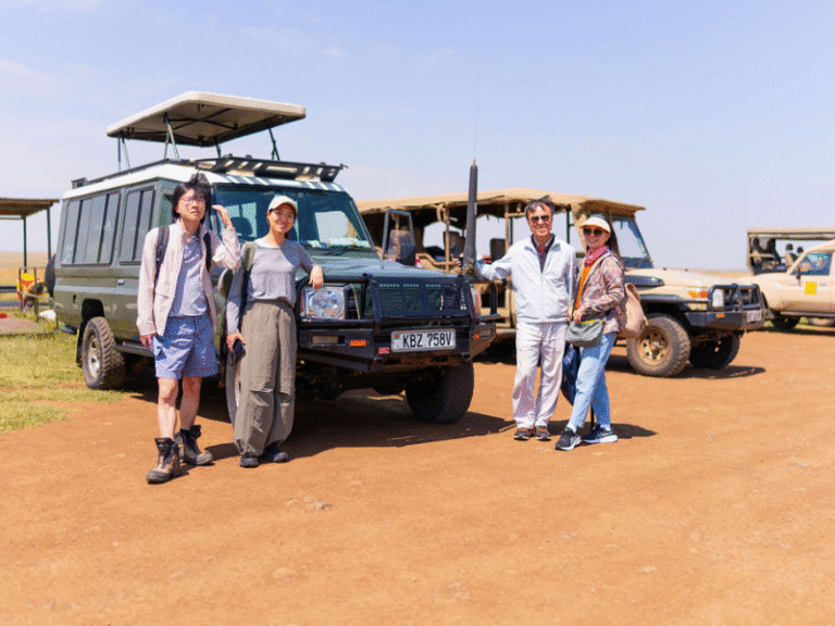 A group of travelers posing in front of open-roof safari vehicles before setting out on a Kenya safari adventure.
