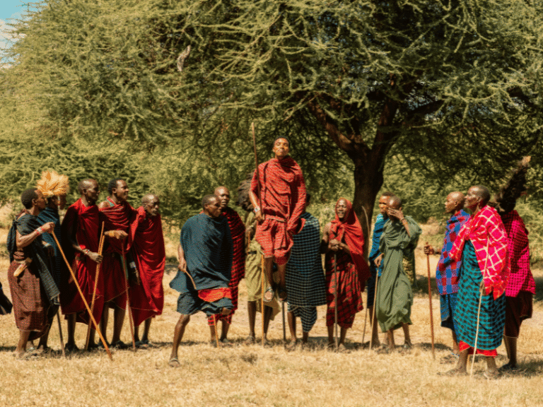 Maasai warriors performing a traditional jumping dance under the shade of a tree in a rural area of Tanzania.