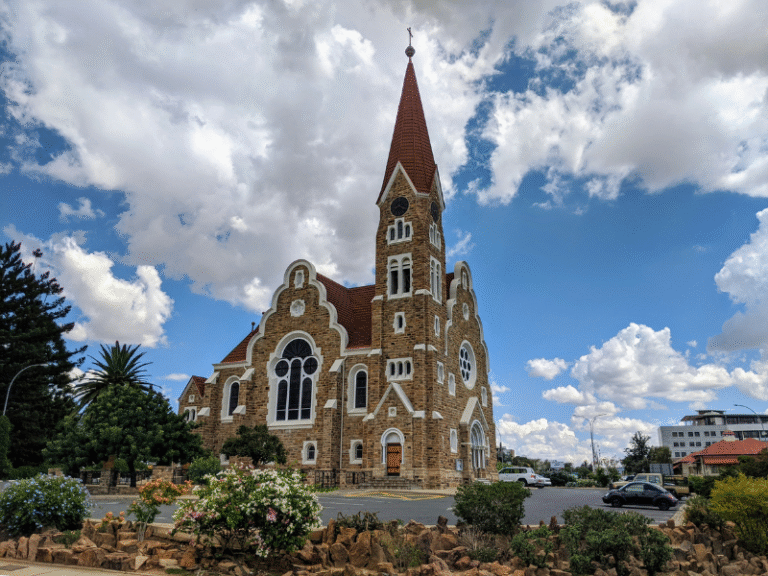 Historic church with red roof and stone walls under a blue sky with clouds in Windhoek, Namibia