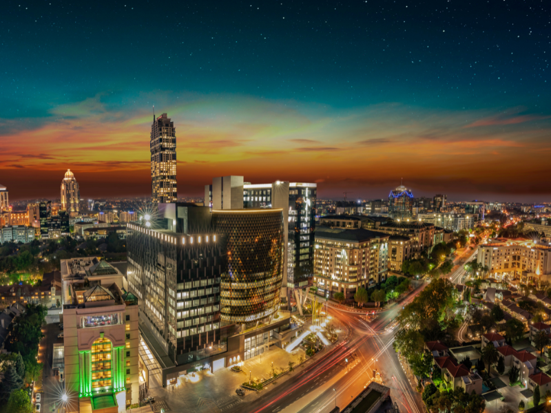 Vibrant Johannesburg skyline at sunset, with illuminated buildings and a bustling cityscape highlighting South Africa’s economic hub.
