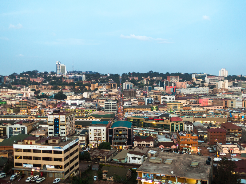 Aerial view of Kampala’s bustling cityscape filled with buildings, traffic and rolling hills.