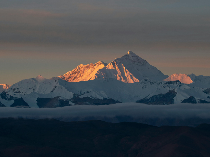 Kilimanjaro vs Everest Base Camp: Which Trek Should You Choose? 5 Golden morning light illuminating the distant snow-covered Himalayas, with clouds drifting low across the valley.