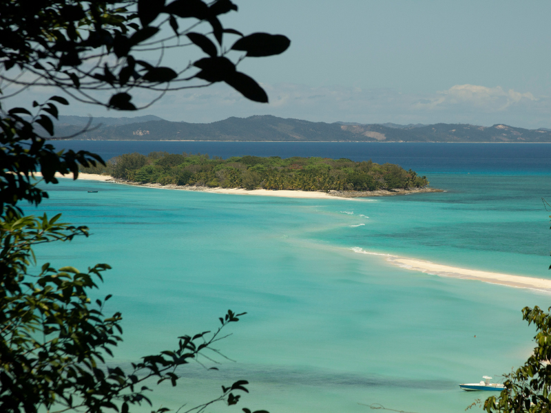 Turquoise waters and white sandy beaches surrounding Nosy Be island in Madagascar, a tropical paradise known for snorkeling and coral reefs.