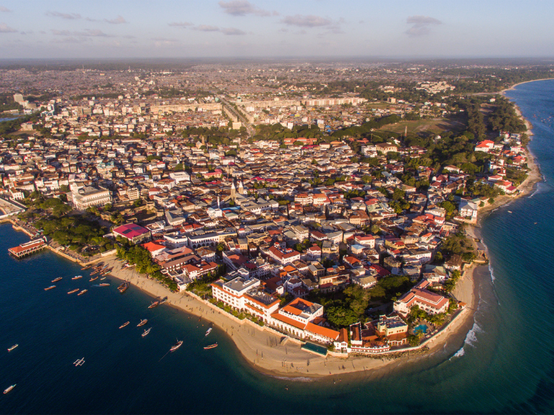 Aerial view of Stone Town, Zanzibar, showing historic buildings, narrow streets, and the coastline.