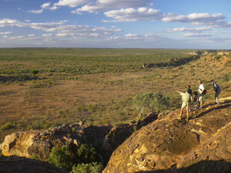 Group of travelers standing on rocky cliffs overlooking a wide, arid savannah in Botswana’s Tuli Block.