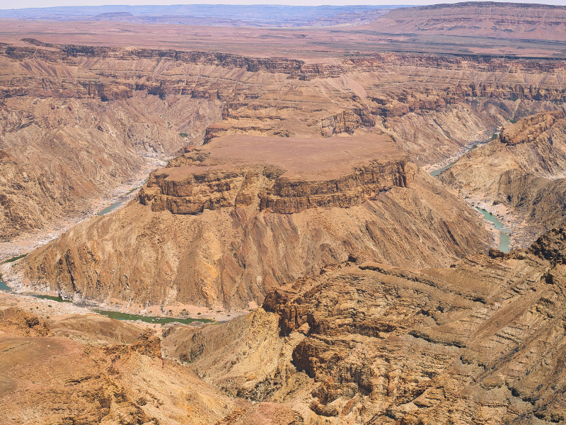 A vast view over Namibia’s Fish River Canyon with rugged rock formations and a winding river far below