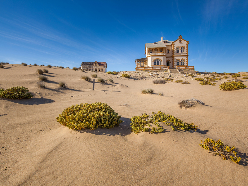 An abandoned historic house surrounded by sand dunes in Kolmanskop, Namibia.