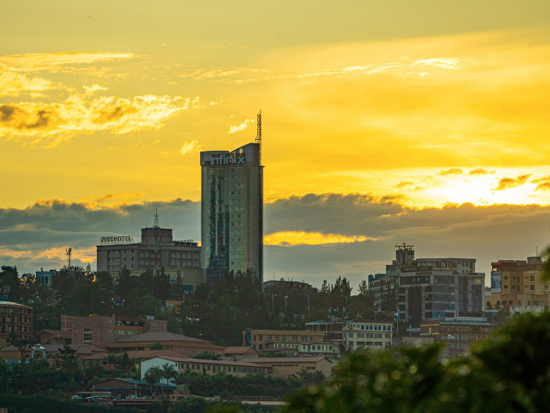 Sunset view of Kigali’s skyline with modern high-rise buildings and warm golden light behind the city.