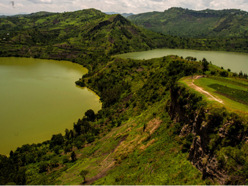 Boat ride on Rwanda’s Twin Lakes with lush green hillsides and volcanic mountains in the background.