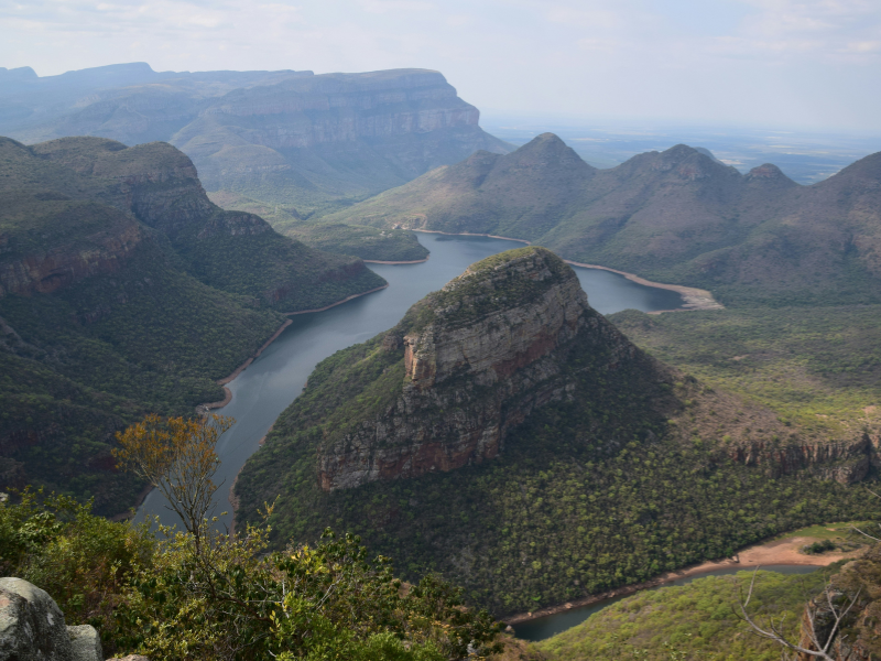 Aerial view of Blyde River Canyon with lush green cliffs and winding blue river channels.