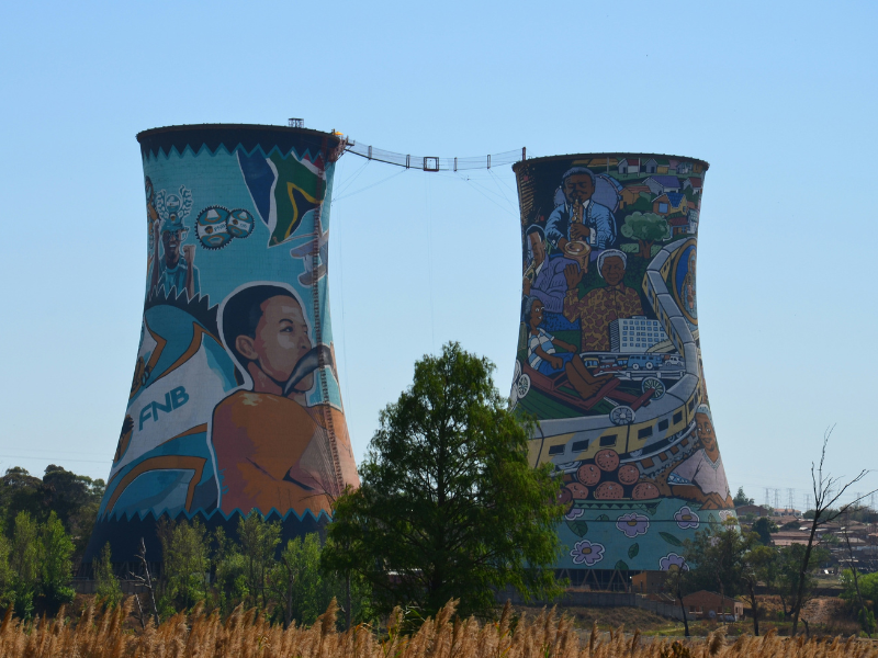 Colorful, mural-covered Orlando Towers rising above trees and buildings in Soweto.