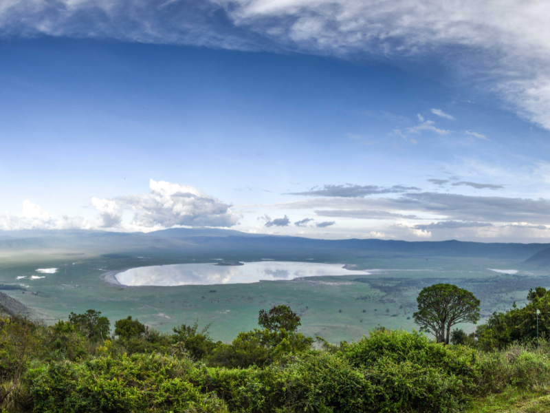 Ngorongoro Crater Tanzania: Facts, History, and What to Expect 1 Panoramic view of a crater lake under big skies, with green plains stretching into the distance