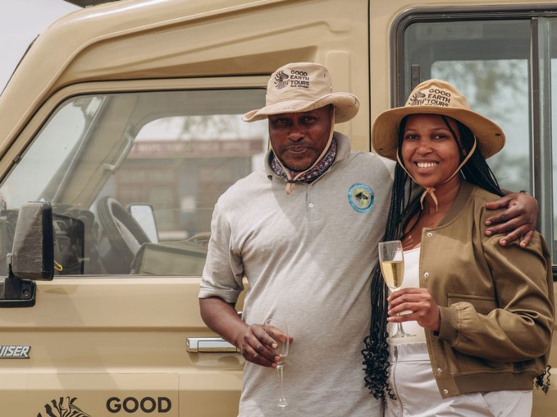 A traveler & guide celebrating at the safari vehicle, a great example of how to book an African safari with expert local support.