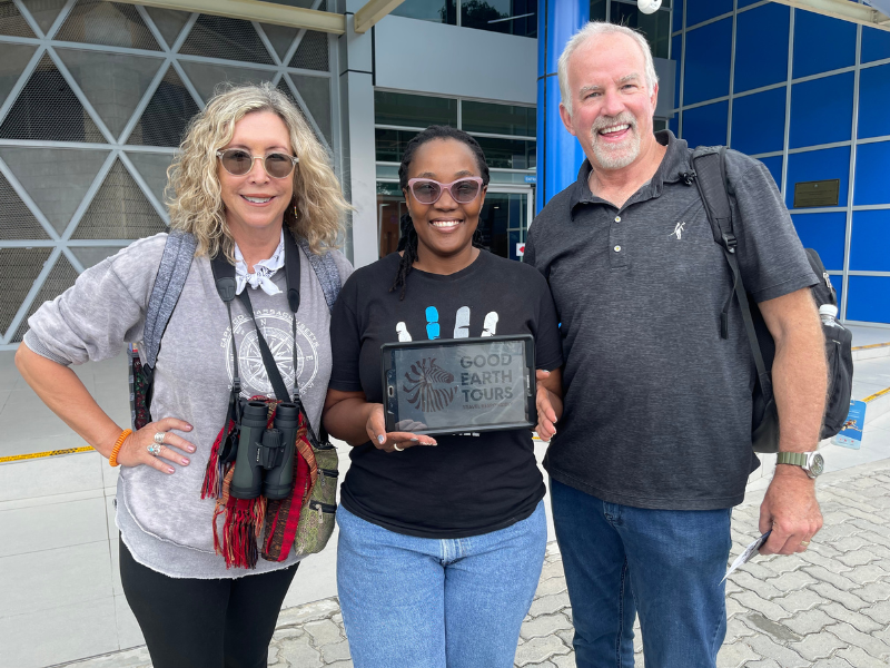 Health benefits of traveling start here: smiling safari guests with a Good Earth Tours welcome sign at the airport