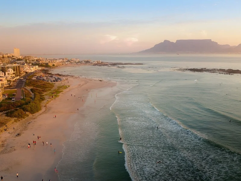 Cape Town beach at sunset with Table Mountain in the distance, warm midsummer weather and gentle waves