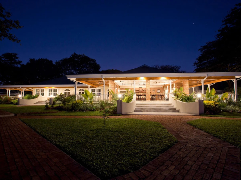 Pioneers Victoria Falls lodge exterior illuminated at night with landscaped gardens.