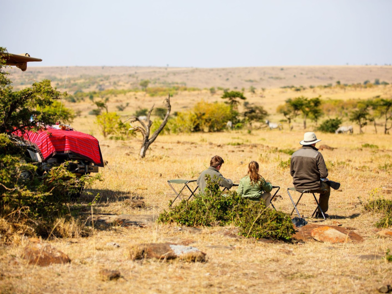 Travelers seated in camp chairs overlooking the savannah during a scenic break, part of what is a typical safari day.